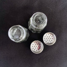 Load image into Gallery viewer, Sail away to flavor-town with this retro vintage set of salt and pepper shakers! These 50s-style clear pressed glass shakers come feature eight panels and flat top stainless steel screw-on lids. Season your food with a real blast from the past! The glass is in excellent condition, free from chips/cracks. The lids have very minor wear, see photos. Marked "TAIWAN". Measures 1 3/8 x 3 inches