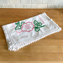 Load image into Gallery viewer, A lovely vintage white cotton dresser scarf or table runner, featuring a sweet hand embroidered pink flowers and green leaves with a pink inner border and beautifully crocheted edge. A gorgeous addition to your linen collection! In good used vintage condition, free from tears, minor stain. Measures 34 1/2 x 15 inches