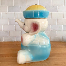 Load image into Gallery viewer, Vintage mid-century hand painted figural white elephant ceramic cookie jar with blue and yellow sailor hat and overalls and pink details. Crafted by American Bisque, USA, circa 1950s. Add some kitsch to your kitchen decor with this adorable collectible!
In excellent condition, no chips or cracks, age-related crazing. Marked USA on the back of the jar.
Measures 8 1/2 x 6 x 10 1/2 inches