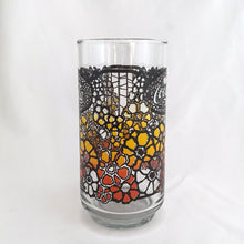 Load image into Gallery viewer, Vintage retro Coca-Cola promotional glass featuring a colourful flower power graphic illustration in an ombre of red, orange and yellow outlined in black. The word "Enjoy" sits above the distinctive Coke logo in a oval medallion reminiscent of a stained glass window. Makers mark is impressed on the bottom, however, we're unable to assign it to a specific maker. In excellent, like new condition, free from chips.