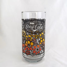 Load image into Gallery viewer, Vintage retro Coca-Cola promotional glass featuring a colourful flower power graphic illustration in an ombre of red, orange and yellow outlined in black. The word "Enjoy" sits above the distinctive Coke logo in a oval medallion reminiscent of a stained glass window. Makers mark is impressed on the bottom, however, we're unable to assign it to a specific maker. In excellent, like new condition, free from chips.