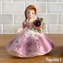 Load image into Gallery viewer, This sweet vintage mid-century figurine is one of the Birthday of the Month series designed by Josef Originals, Japan, 1950s. This sweet black-eyed girl is beautifully styled wearing a full length gown, hand painted in purple with raised flowers, holding a purple flowers with an amethyst birthstone in the centre of the flower. In excellent condition, free from chips/cracks/repairs. Marked on the bottom with the Noritake for Giftcraft mark. Measures 3 1/2 x 4 inches