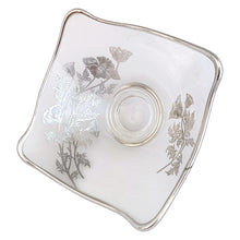 Load image into Gallery viewer, Vintage Flanders clear candy bowl features a silver overlay pattern of poppy flowers. The blank is Viking Glass and the overlay is by Silver City Glass, USA, 1940s. his lovely square bowl with folded corners is perfect for serving candies or to use as a catchall. A lovely way to add a touch of vintage charm to your home or to give as housewarming or wedding gift.
In excellent condition, no chips. Silver is intact.
Measures 6 x 3 inches