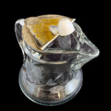 Load image into Gallery viewer, Sweet vintage cut crystal syrup pitcher featuring cut flowers and stems with removable metal hinged lid and applied blown handle. Crafted by Heisey Glass, USA, circa 1920s. A beautiful addition to your tablescape!
In great vintage condition, no chips, wear to the lid.
Measures 3 1/8 x 3 inches