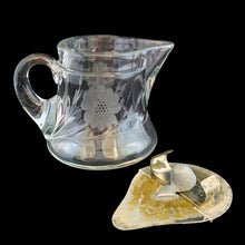Load image into Gallery viewer, Sweet vintage cut crystal syrup pitcher featuring cut flowers and stems with removable metal hinged lid and applied blown handle. Crafted by Heisey Glass, USA, circa 1920s. A beautiful addition to your tablescape!
In great vintage condition, no chips, wear to the lid.
Measures 3 1/8 x 3 inches