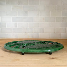Load image into Gallery viewer, side view of Cast iron trivet with fish motif, close-up detail of fish design and green enamel surface