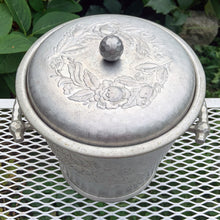 Load image into Gallery viewer, Vintage mid-century era Roses hand forged hammered aluminum ice bucket featuring two stylized handles, an embossed rose sprays on each side of the bucket plus a wreath of roses on the lid circling the decorative knob. Crafted by the Everlast Metal Products Corporation, USA, 1950s. Includes a decorative hammered aluminum slotted ice spoon. The perfect addition to your bar cart!
In used vintage condition with age-appropriate wear. Measures 8 x 8 x 9 1/2 inches