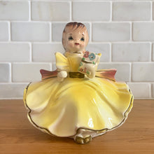 Load image into Gallery viewer, Adorable vintage mid-century era girl in a yellow dress ceramic planter 502. Crafted by Rubens Originals, Japan, 1950s. Use for tiny plants or repurpose to hold accessories.
In as found vintage condition, bow is chipped at the back, no cracks/repairs.
Measures 4 1/2 x 4 x 4 1/2 inches