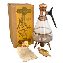 Load image into Gallery viewer, Vintage MCM glass coffee carafe features copper stripes, a black atomic-age bakelite handle, copper cork stopper and metal beauty bowl warmer stand. Crafted by Inland Glass, USA, 1950s. A fabulous mid-century serving piece for yourself or to give as a gift!
In excellent condition. New in box with tags, instructions and 2 candles.
Measures 6 x 9 1/2 inches, spout 2 1/8 inches