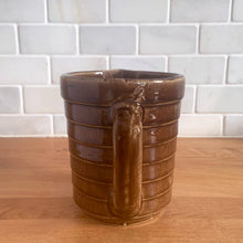 Load image into Gallery viewer, Vintage glossy caramel brown stoneware pitcher with horizontal ribbed detail. Crafted by Monmouth Western Stoneware, USA, 1920s. Add this utilitarian piece to your farmhouse decor or art pottery collection!
In excellent condition, no chips/cracks/repairs, age-related crazing. Unmarked.
Measures 4 1/2 x 5 inches