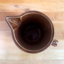 Load image into Gallery viewer, Vintage glossy caramel brown stoneware pitcher with horizontal ribbed detail. Crafted by Monmouth Western Stoneware, USA, 1920s. Add this utilitarian piece to your farmhouse decor or art pottery collection!
In excellent condition, no chips/cracks/repairs, age-related crazing. Unmarked.
Measures 4 1/2 x 5 inches
