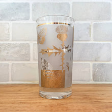 Load image into Gallery viewer, A chilled cocktail would complement this vibrant vintage Golden Meadow highball glass tumbler featuring 22kt gold. Designed by Fred Press and produced by the Federal Glass, USA, circa 1960-70. The gold butterfly and botanical details pop off the frosted background.
In excellent condition, no chips, minor spot of wear on one glass.
Measures 2 3/4 x 5 1/8 inches