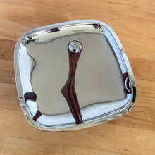 Load image into Gallery viewer, Straight out of the atomic age, this "Gourmates" chrome single tier serving tidbit tray with amber Bakelite legs and handle delivers loads of mid-century modern vibe to entertaining. This piece appears to be new old stock and is super shiny. Produced by Glo-Hill in Canada, circa 1960s. A stylish way to serve anything from appetizers to chocolates! In excellent condition and looks brand spanking new! Measures 7 1/8 x 7 1/8 x 4 3/4 inches