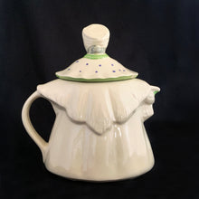 Load image into Gallery viewer, Vintage cream coloured figural "Granny Ann" ceramic teapot featuring a sweet granny holding a brown cane and dressed in a hat and garden frock in green and purple. Crafted by Shawnee Pottery, USA, circa 1940s. Even the spout is a figural basket! In excellent condition, free from chips/cracks/repairs. Marked on the bottom, "Patented Granny Ann U.S.A." Measures 8 x 5 5/8 x 8 1/2 inches