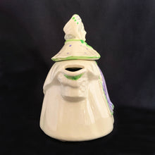 Load image into Gallery viewer, Vintage cream coloured figural "Granny Ann" ceramic teapot featuring a sweet granny holding a brown cane and dressed in a hat and garden frock in green and purple. Crafted by Shawnee Pottery, USA, circa 1940s. Even the spout is a figural basket! In excellent condition, free from chips/cracks/repairs. Marked on the bottom, "Patented Granny Ann U.S.A." Measures 8 x 5 5/8 x 8 1/2 inches