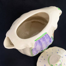 Load image into Gallery viewer, Vintage cream coloured figural "Granny Ann" ceramic teapot featuring a sweet granny holding a brown cane and dressed in a hat and garden frock in green and purple. Crafted by Shawnee Pottery, USA, circa 1940s. Even the spout is a figural basket! In excellent condition, free from chips/cracks/repairs. Marked on the bottom, "Patented Granny Ann U.S.A." Measures 8 x 5 5/8 x 8 1/2 inches