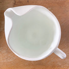 Load image into Gallery viewer, The words "stunning" and "elegant" embody this incredible milk glass pitcher in the "Harvest" pattern of grapes and vines. This is the largest version in this series holding 72oz. Made by Colony (Indiana) Glass Co. Circa 1966. This pitcher would look amazing on any tablescape or use it for a beautiful floral bouquet. In excellent condition, no chips or cracks. Measures 6 x 10 3/8 inches