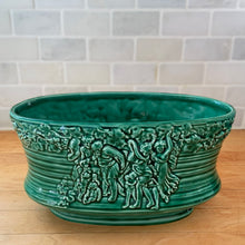 Load image into Gallery viewer, Vintage green glazed Bacchante oval planter jardiniere, shape 115, features embossed toga-clad figures with grapevine detail at the rim. Crafted by Sylvac, England, 1930s 1940s. A nice sized piece for your favourite bulbs and houseplants or use as decor.
In excellent condition, no chips/cracks/repairs.
Measures 9 1/4 x 5 3/4 x 5 1/2 inches
