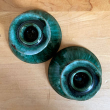 Load image into Gallery viewer, Overhead view of both candle holders showing the full green drip glaze surface, teal-to-black gradient, and central candle spike openings, on wood surface