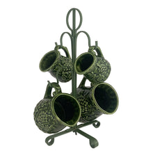 Load image into Gallery viewer, Vintage set of four dark green glazed ceramic measuring cups which hang on a green metal stand. Crafted by Noritake, Japan, 1960s. The cups feature an embossed grapevine pattern with flower borders. Each cup is marked, 1 cup, 1/2 cup, 1/4 cup and 1/8 cup. A sweet and practical piece of kitchen decor! Overall good vintage condition. The 1/2 cup has a glaze chip on the rim and the 1/4 cup measure has a tiny flea bite on the handle, see photos.