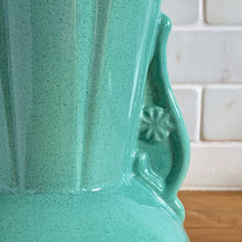 Load image into Gallery viewer, Vintage Art Deco green speckle glazed ceramic flower vase featuring a round base and a ribbed panel design flanked by two handles highlighted with a flower motif. Crafted by York Pottery (precursor to Pfaltzgraff), USA, circa 1930s. A beautiful piece to add to any art pottery collection! Excellent condition. Marked with impressed keystone, York P 288 USA. Measures 5 x 8 inches