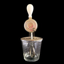 Load image into Gallery viewer, Vintage A&J clear depression era glass 1 pint (2 cup) hand beater mixer with white wood handle. The glass cup has measuring lines in 1/2 cup increments up to the 1 cup line and 1/4 cup increments up to the 2 cup line and the reverse in 2 ounce increments. Crafted by Hazel-Atlas Glass, circa 1920s. Perfect for beating eggs or mixing salad dressings.
In as found vintage condition, with wear.