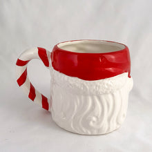 Load image into Gallery viewer, A hand painted vintage happy Santa Claus ceramic mug decorated in red, white, green and black plus a candy cane striped handle! Crafted in Taiwan, circa 1980s. Add charm to your Christmas decor by filling this adorable mug with candy canes! In excellent vintage condition, free from chips/cracks/repairs with one minor spot of glaze loss on the green holly leaf. Measures 3 1/2 x 3 1/4 inches