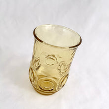 Load image into Gallery viewer, Vintage retro "Heritage Hill" honey gold 6 oz flat juice glass. Crafted by Anchor Hocking, USA, circa 1976. These glasses feature a textured finish with 6 embossed circles around the body, a flared top and tapered base. Perfect for the bevvy of your choice...cheers! In excellent condition, free from chips, minimal wear. Measures 2 1/4 x 3 3/4 inches Capacity 6 ounces