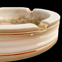 Load image into Gallery viewer, Vintage ceramic ashtray featuring hand painted pink hibiscus flower and green leaves on an cream ground with gold details. Crafted by Torretti Deruta, Italy, 1960s. A beautiful decorative ceramic ashtray! In vintage condition, minor chip, see photos, otherwise excellent. Measures 5 1/2 x 1 3/4 inches