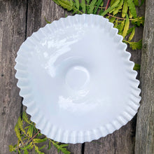 Load image into Gallery viewer, This vintage "Hobnail" pressed milk glass low banana stand brings all the drama! It features a low foot, with folded sides and a crimped edge. Crafted by the Fenton Art Glass, USA, circa 1970s. A graceful piece of pressed glass in a classic pattern that will always be in style no matter your decor style. Fill with your favourite fruits and display! In excellent condition, free form chips/cracks. Measures 12 x 9 x 4 1/2 inches