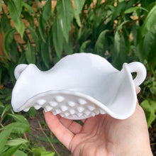 Load image into Gallery viewer, This vintage milk glass "Hobnail" 7 inch pressed glass handled bon bon dish brings all the drama in a small package! It features a square bowl with scalloped edge and two handles. Crafted by the Fenton Art Glass, USA, circa 1960s. A graceful piece of pressed glass in a classic pattern that will always be in style no matter your decor style! Fill with your favourite candies, nuts or snacks. In excellent condition, free form chips/cracks. Measures 7 x 7 x 2 1/2 inches (from corner to corner)