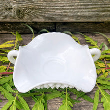 Load image into Gallery viewer, This vintage milk glass "Hobnail" 7 inch pressed glass handled bon bon dish brings all the drama in a small package! It features a square bowl with scalloped edge and two handles. Crafted by the Fenton Art Glass, USA, circa 1960s. A graceful piece of pressed glass in a classic pattern that will always be in style no matter your decor style! Fill with your favourite candies, nuts or snacks. In excellent condition, free form chips/cracks. Measures 7 x 7 x 2 1/2 inches (from corner to corner)