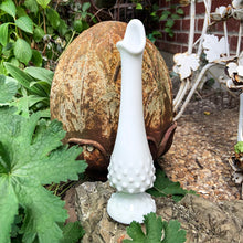Load image into Gallery viewer, This vintage milk glass "Hobnail" handled swung bud vase brings all the drama in a small package! Crafted by the Fenton Art Glass, USA, circa 1960s. A graceful piece of mold blown and hand pulled glass in a classic pattern that will always be in style no matter your decor style! In excellent condition, free form chips/cracks. Measures 2 1/2 x 9 1/8 inches