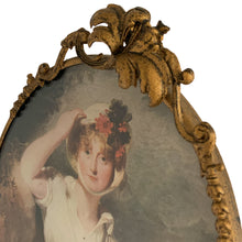 Load image into Gallery viewer, Vintage mid-century Hollywood Regency ornate brass oval shaped frame featuring a three dimensional Hibiscus flower with decorative treatment holding a lithographic print of Caroline Princess of Wales by Sir Thomas Lawrence (1798). This piece has a stand so it can be displayed on a table and it also has a hanger to facilitate hanging on a wall. The back is removable making it a breeze to change the artwork. A lovely piece! In excellent condition. Measures 7 1/8 x 10 inches