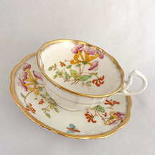 Load image into Gallery viewer, Vintage bone china Avon shaped "Honeysuckles" teacup and saucer. Each piece has a lovely scalloped edge featuring a hand painted Honeysuckle vines and bees in shades of orange, pink, yellow, blue and green, trimmed with gold gilt. Crafted by Royal Albert, England, circa 1927 to 1935. Makes a beautiful gift or addition to your collection!