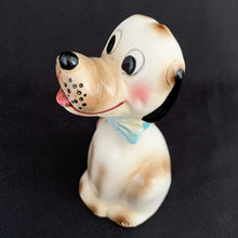 Load image into Gallery viewer, Show off the playful charm of this adorably freckle faced ceramic hound dog figurine! Its wide-eyed expression and pink tongue will add a dash of fun to any room. This beige, tan and black canine features a classic blue bow tie and is sure to charm everyone who sees it! In excellent condition, free form chips/cracks/repairs. Marked "Japan" on the bottom. Measures 2 x 4 1/2 inches