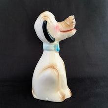 Load image into Gallery viewer, Show off the playful charm of this adorably freckle faced ceramic hound dog figurine! Its wide-eyed expression and pink tongue will add a dash of fun to any room. This beige, tan and black canine features a classic blue bow tie and is sure to charm everyone who sees it! In excellent condition, free form chips/cracks/repairs. Marked "Japan" on the bottom. Measures 2 x 4 1/2 inches