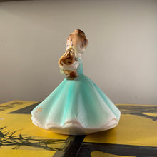 Load image into Gallery viewer, This sweet vintage mid-century figurine is one of the Birthday of the Month series designed by Josef Originals of Japan, circa 1950s. This sweet girl is beautifully styled wearing a full length dress hand painted in aqua and gold, holding a basket of yellow flowers with an aquamarine birthstone in the centre of each flower. In excellent condition, free from chips/cracks/repairs. Marked on the bottom "Josef Originals © Japan" Measures 3 1/2 x 4 inches