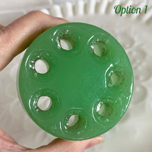Load image into Gallery viewer, Jadeite green glass flower frog held in hand, close-up on the underside