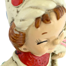 Load image into Gallery viewer, Close-up of the Josef Originals Libra wizard figurine face, showing hand-painted features including closed lash-lined eyes, rosy cheeks, brown moulded hair with chip visible at hairline, red textured collar, white wizard hat above