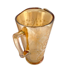 Load image into Gallery viewer, Gorgeous vintage mid century era iridescent marigold carnival glass pitcher featuring the "Late Sunflowers" pattern of wildflowers and ferns in white. Crafted by Jeannette Glass, USA, 1950s. The perfect way to serve your favourite beverage with vintage flare! In excellent condition, minor wear. Flea bites along the mold release at the interior rim, see photos. Measures 5 5/8 x 9 5/8 inches Capacity 56 ounces