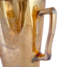 Load image into Gallery viewer, Gorgeous vintage mid century era iridescent marigold carnival glass pitcher featuring the "Late Sunflowers" pattern of wildflowers and ferns in white. Crafted by Jeannette Glass, USA, 1950s. The perfect way to serve your favourite beverage with vintage flare! In excellent condition, minor wear. Flea bites along the mold release at the interior rim, see photos. Measures 5 5/8 x 9 5/8 inches Capacity 56 ounces