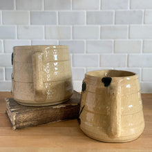 Load image into Gallery viewer, Vintage natural yellow ware strapped barrel milk pitcher featuring navy lily in bas relief with rope style handle, No. 21171. Crafted by Robinson Ransbottom Pottery Co., USA, 1930s. Enhance your home's decor with this beautiful piece of primitive farmhouse tableware. A wonderful addition to any art pottery collection!
Excellent vintage condition, no chips/cracks/repairs, age-related crazing and typical manufacturer's glaze pops. Unmarked
Option 1: 4 x 4 1/8 inches. 32 oz
Option 2: 5 1/4 x 5 1/4. 48 oz