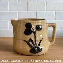 Load image into Gallery viewer, Vintage natural yellow ware strapped barrel milk pitcher featuring navy lily in bas relief with rope style handle, No. 21171. Crafted by Robinson Ransbottom Pottery Co., USA, 1930s. Enhance your home's decor with this beautiful piece of primitive farmhouse tableware. A wonderful addition to any art pottery collection!
Excellent vintage condition, no chips/cracks/repairs, age-related crazing and typical manufacturer's glaze pops. Unmarked
Option 2: 5 1/4 x 5 1/4. 48 oz