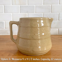 Load image into Gallery viewer, Vintage natural yellow ware strapped barrel milk pitcher featuring navy lily in bas relief with rope style handle, No. 21171. Crafted by Robinson Ransbottom Pottery Co., USA, 1930s.
Enhance your home's decor with this beautiful piece of primitive farmhouse tableware. A wonderful addition to any art pottery collection!
Option 3: Measures 4 x 4 1/2 inches. In excellent vintage condition, no chips/cracks/repairs with age-related crazing and typical manufacturer's glaze pops. Unmarked. Capacity 32 ounces