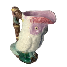 Load image into Gallery viewer, Antique majolica figural white and pink cockatoo parrot ceramic pitcher with green botanical base and brown bamboo-style handle. Crafted by Georges Jones, England, in the late 19th century (1880s). A wonderful piece of whimsical majolica for any collector and lends itself nicely to a tropical or Tiki themed decor!
In good used vintage condition, no chips. Age-related crazing and typical manufacturing glaze bubbles present. See photos.
Measures 5 x 2 1/2 x 6 inches