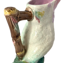 Load image into Gallery viewer, Antique majolica figural white and pink cockatoo parrot ceramic pitcher with green botanical base and brown bamboo-style handle. Crafted by Georges Jones, England, in the late 19th century (1880s). A wonderful piece of whimsical majolica for any collector and lends itself nicely to a tropical or Tiki themed decor!
In good used vintage condition, no chips. Age-related crazing and typical manufacturing glaze bubbles present. See photos.
Measures 5 x 2 1/2 x 6 inches