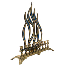 Load image into Gallery viewer, A beautifully crafted vintage brass nine candle Hanukkah menorah with flame motif inset with blue enamel. Made in Israel. A beautiful way to celebrate the Festival of Lights!
In good vintage condition with wear and patina.
Measures 9 5/8 x 2 7/8 x 10 1/2 inches
