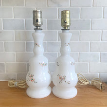 Load image into Gallery viewer, A beautifully shaped pair of vintage milk glass table lamps featuring hand painted flowers in orange, green and gold. Perfect for adding vintage charm to any space. In as found vintage condition, glass is free from chips/cracks, paint is worn. Tested and in working order. Measures 3 7/8 x 12 1/4 inches
