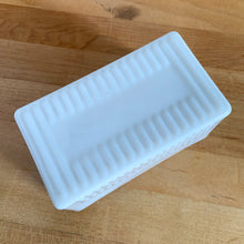 Load image into Gallery viewer, Vintage style milk glass butter dish lid features raised ribs and the word "BUTTER" in reverse on the inside. Crafted by Abbott Industries. Even without it's bottom, this is a versatile piece that could be repurposed as a catchall, for bath accessories or as a planter. In excellent condition, no chips. Measures 5 5/8 x 3 1/8 x 2 3/4 inches